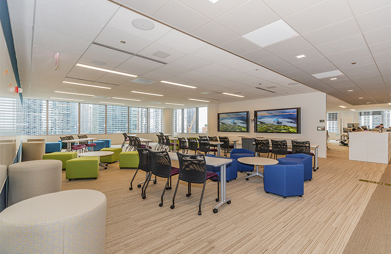 An open collaborative workspace with natural light, modern decor and large wall-mounted screens