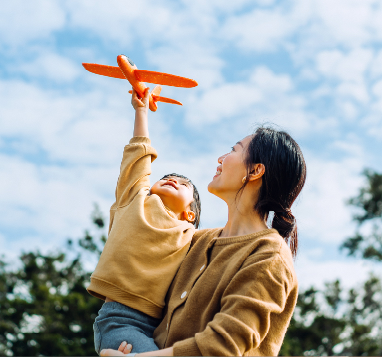 Mother holds young boy who plays with toy airplane