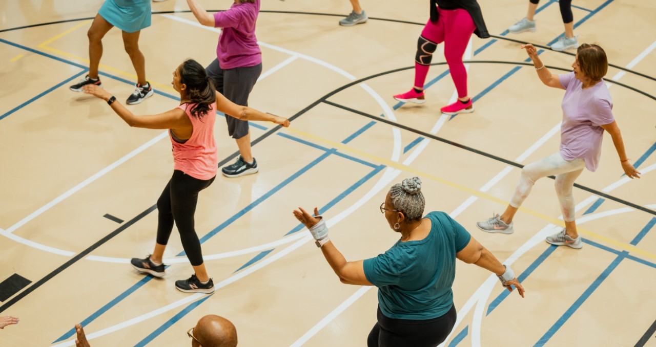 A gym of seniors dances in sync during a workout class