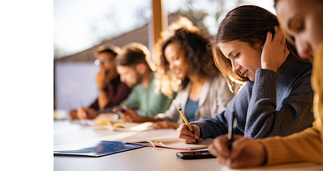 A row of students reading and writing in notebooks