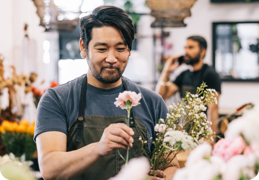 A man picking a putting together a flower arrangement. 