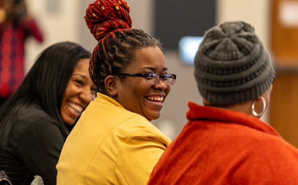 Three women laugh together at event