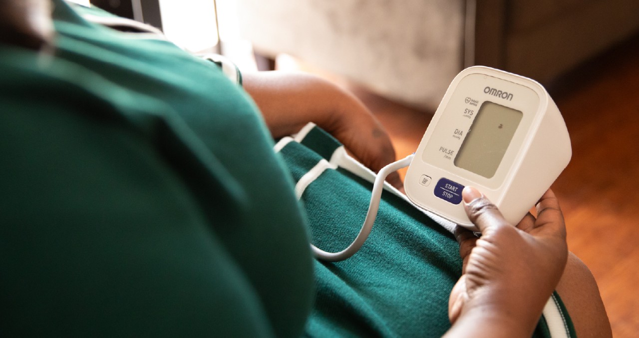 Woman sits holding a digital blood pressure device