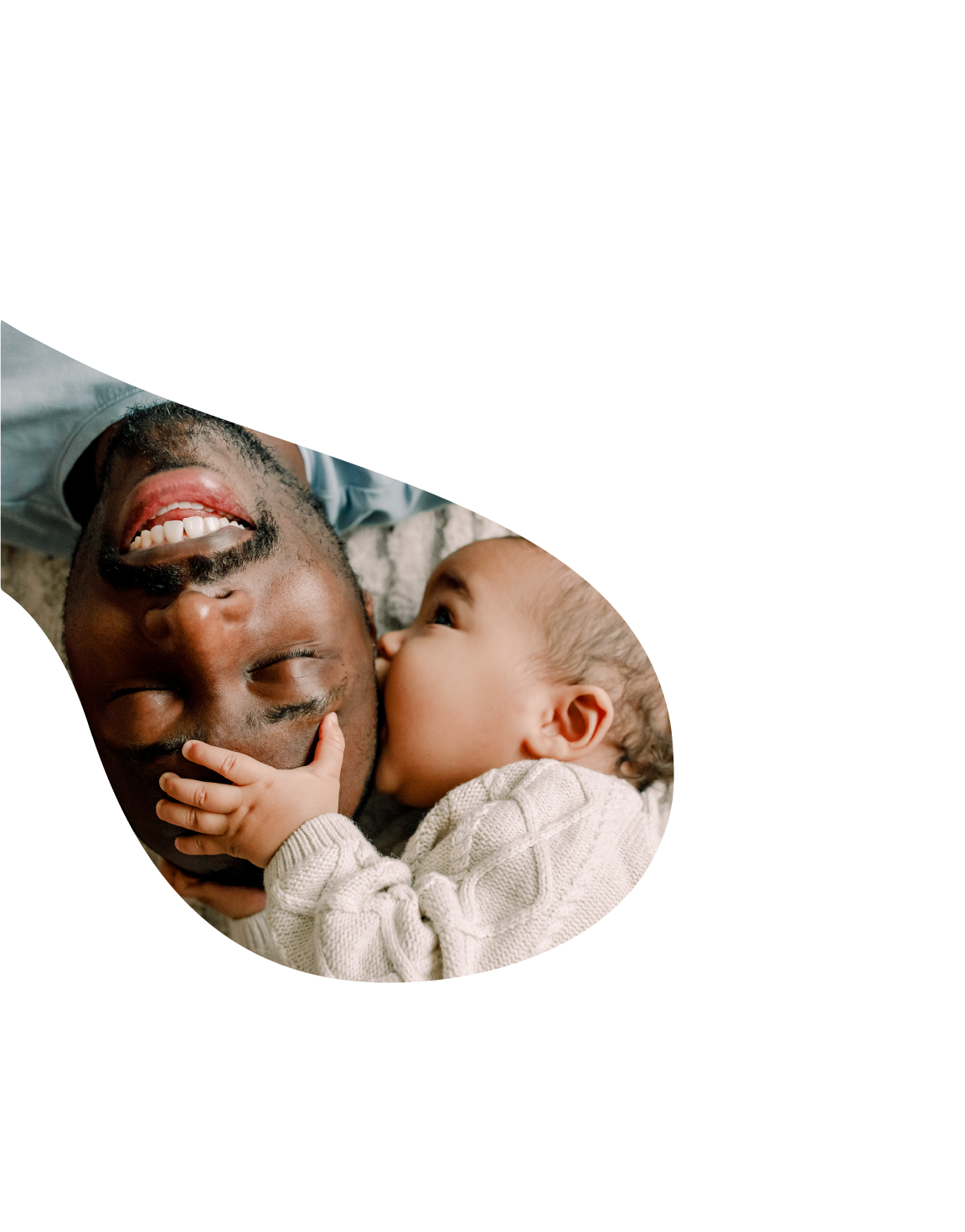 An African American man smiles as his small child hugs his head
