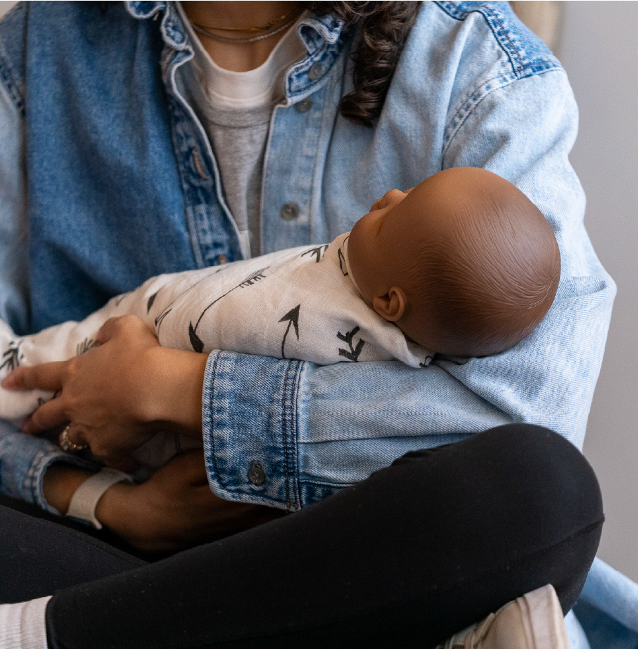 A young woman cradles a swaddled infant doll during a training session for doulas.
