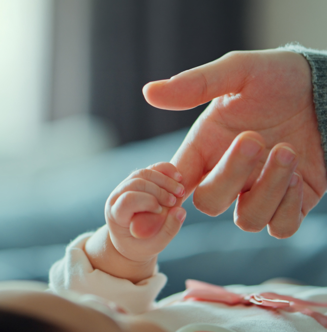 A clinician's hand holds a stethoscope to a pregnant woman's abdomen. 