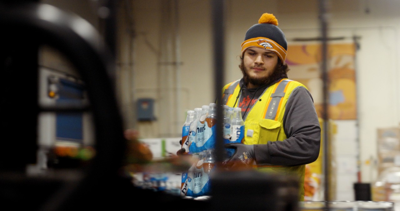 Feeding America worker carries packages of bottled water