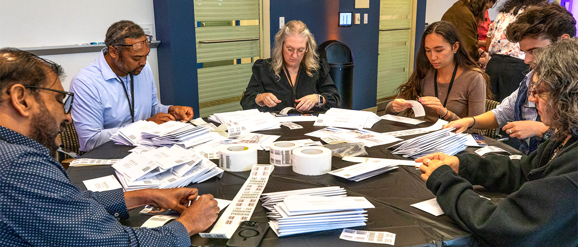 People sit at table and prepare envelops