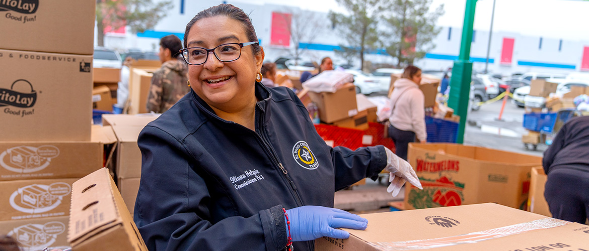 Woman smiles as she prepares to distrbute food at a food back