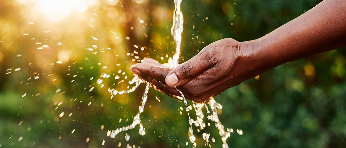 Water flows into an outstretched hand on a sunny day