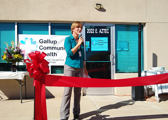 Woman speaks at a ribbon-cutting ceremony in front of a health clinic
