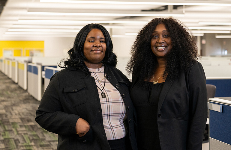 Two women pose for a photo at their office