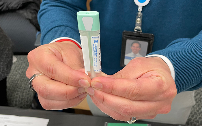 Hands hold part of an at-home test kit used for colorectal cancer screening.