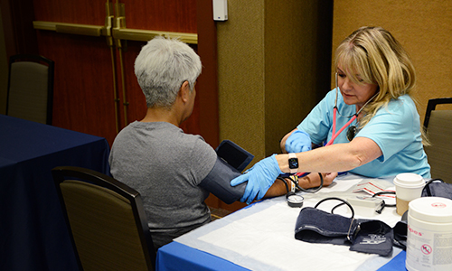 Seated nurse takes blood pressure of older woman