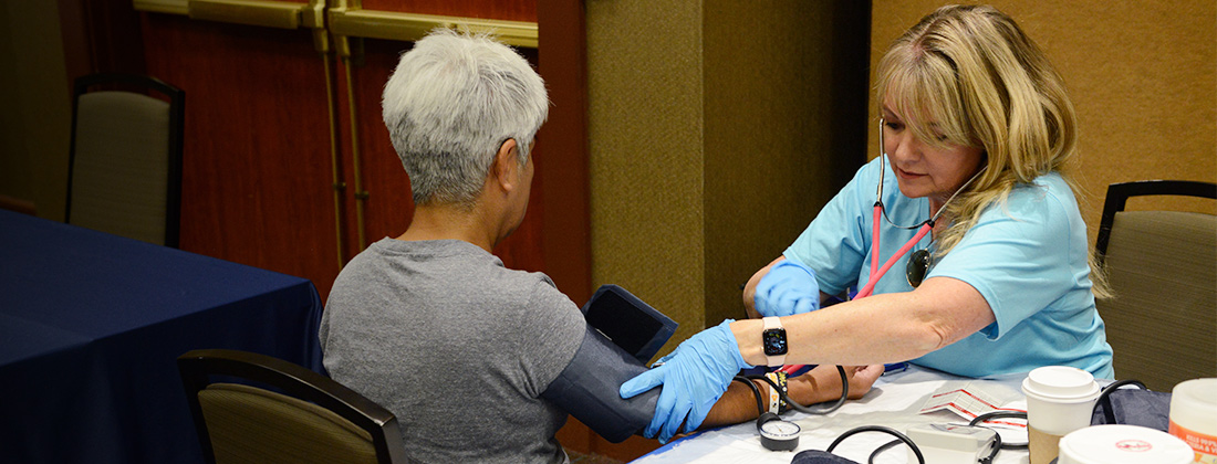 Seated nurse takes blood pressure of older woman
