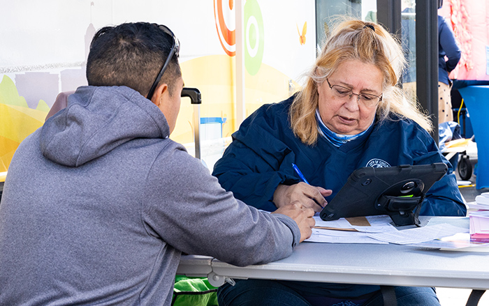 A women helps a man sign in for vaccinations. 