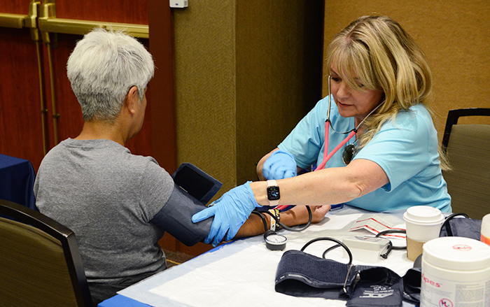 Seated nurse takes blood pressure reading of older woman