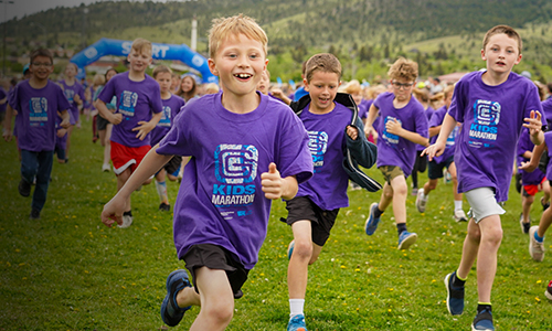 Kids dressed in purple run outdoors during community health marathon