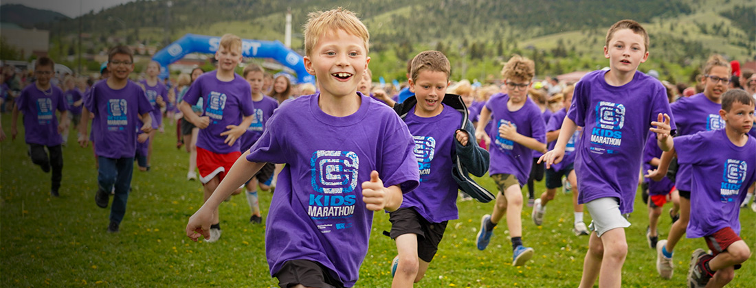 Kids dressed in purple run outdoors during community health marathon